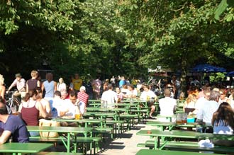 MUC Munich - people relaxing in the beer garden in the middle of the English Garden with blossoming chestnut trees 3008x2000