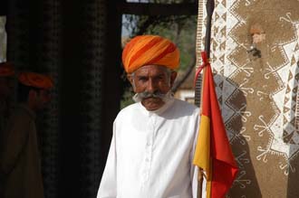 DEL Mandawa in Shekawati region - Hotel Mandawa Desert Resort doorman with orange-red turban and flag 3008x2000