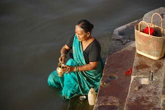 VNS Varanasi or Benares - woman preparing to disperse ashes of a cremated body in the holy Ganges river 3008x2000