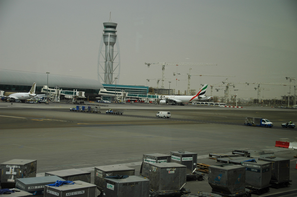 DXB Dubai International Airport - Terminal 1 with Tower, aircrafts at the gates and air-cargo containers in the foreground 3008x2000