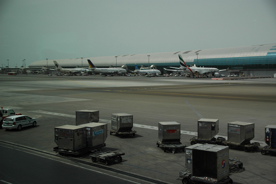 DXB Dubai International Airport - Terminal 1 with aircrafts at the gates and air-cargo containers in the foreground 3008x2000