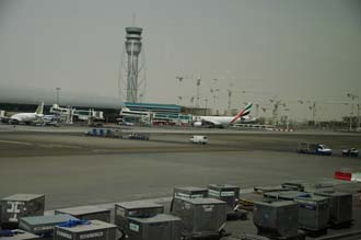 DXB Dubai International Airport - Terminal 1 with Tower, aircrafts at the gates and air-cargo containers in the foreground 3008x2000